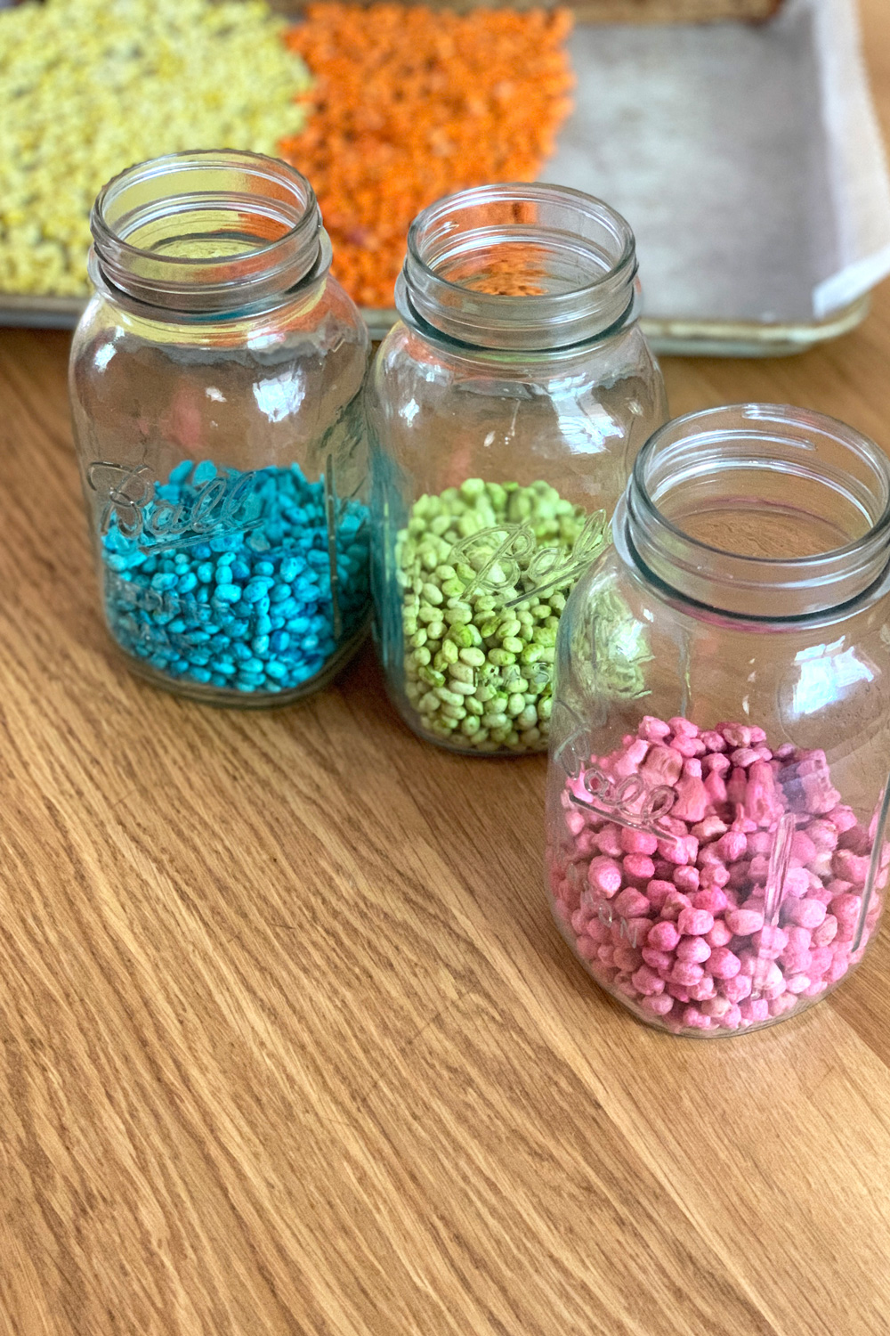 Three jars of beans in blue, green, and pink.
