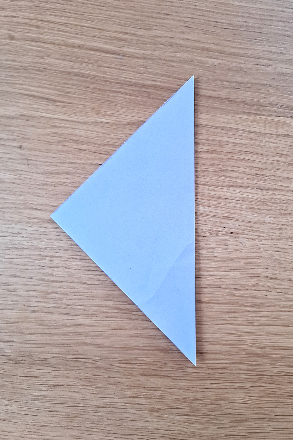 A square of paper folded in half to make a triangle.