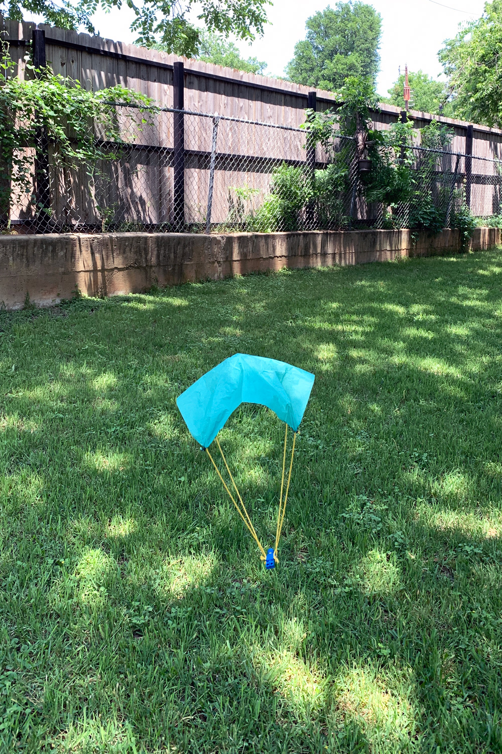 DIY parachute landing on the grass in a backyard.