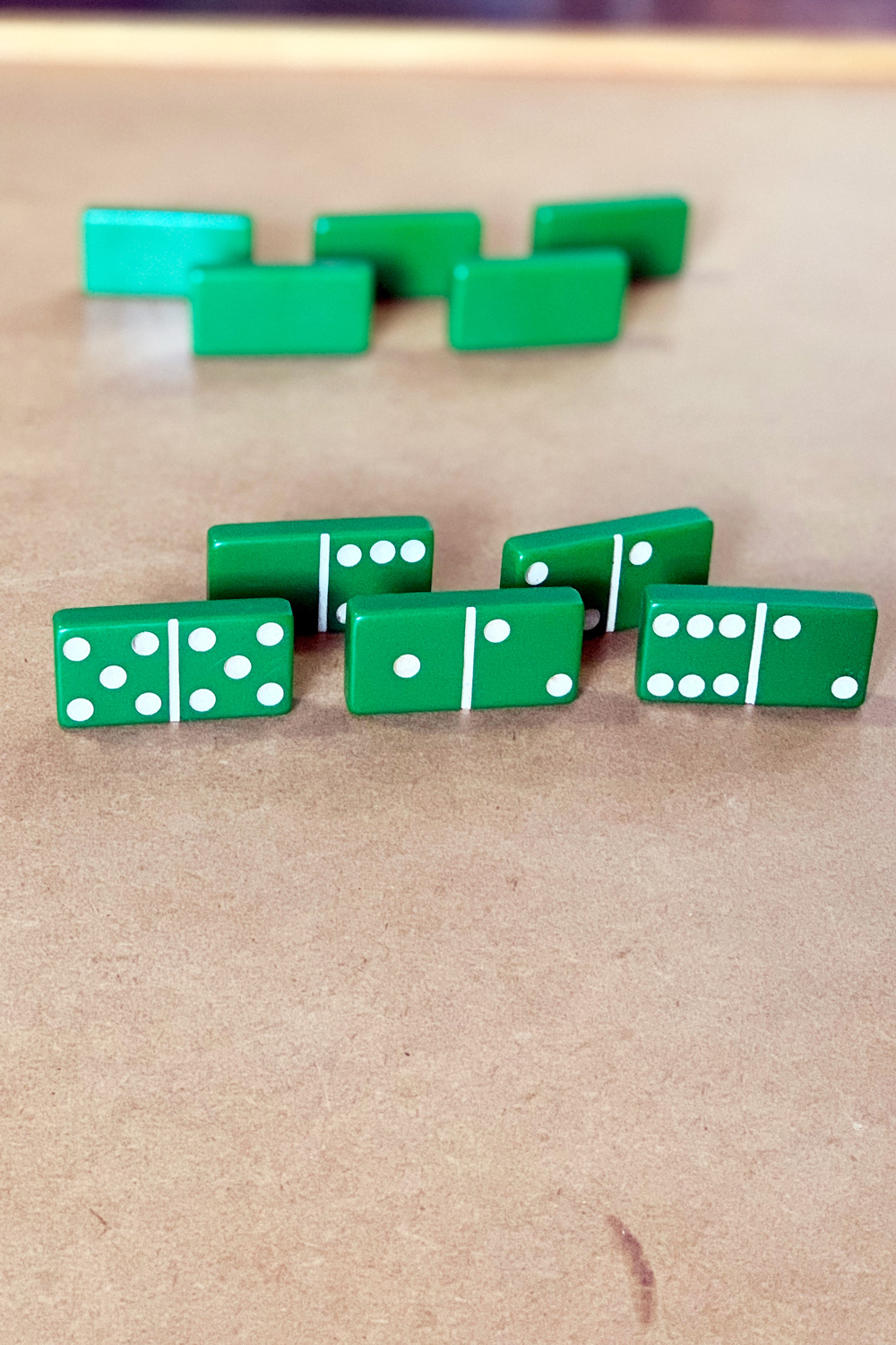 A hand of 5 dominoes lined up on their ends so only the viewer can see the pips.