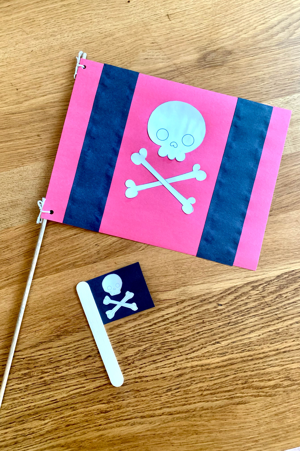 A red and black pirate flag beside a tiny black flag, both with a white skull and crossed bones in the center.