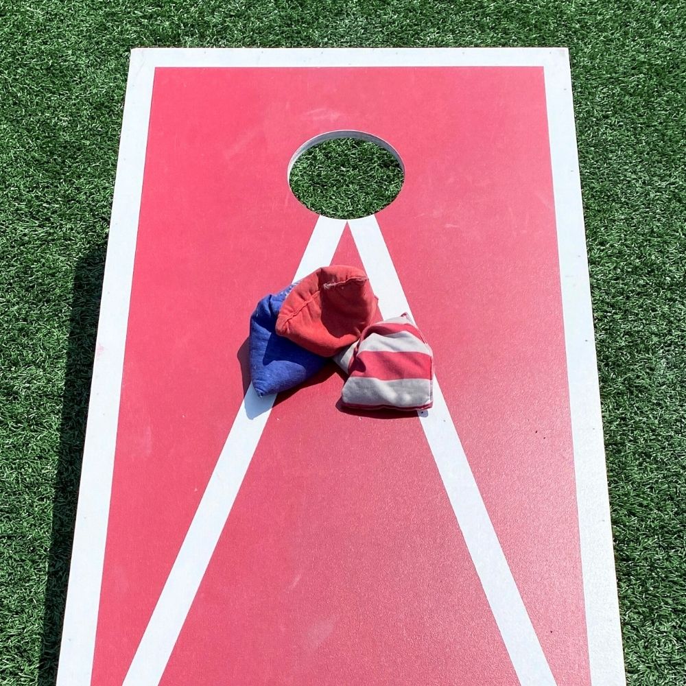 Three beanbags missing the opening in a cornhole game board.