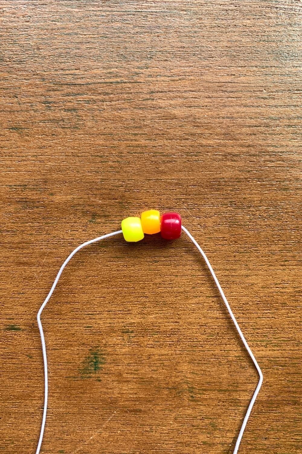 Yellow, orange, and red pony beads on elastic cord.