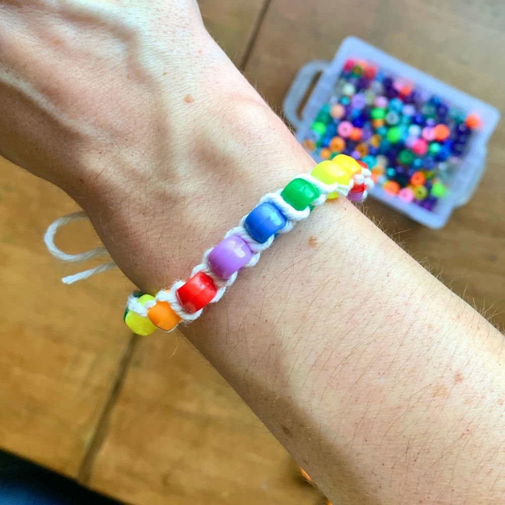 A rainbow pony bead bracelet on someone's wrist.