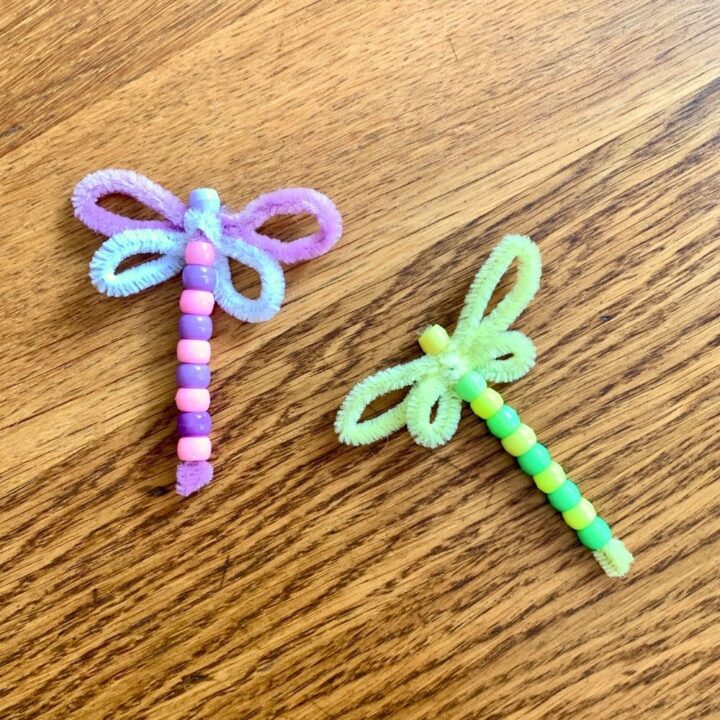 Two pipe cleaner dragonfly crafts made with pink/purple and green/yellow beads.