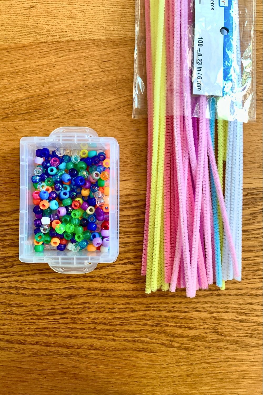 A box of colorful pony beads beside a package of pastel pipe cleaner.