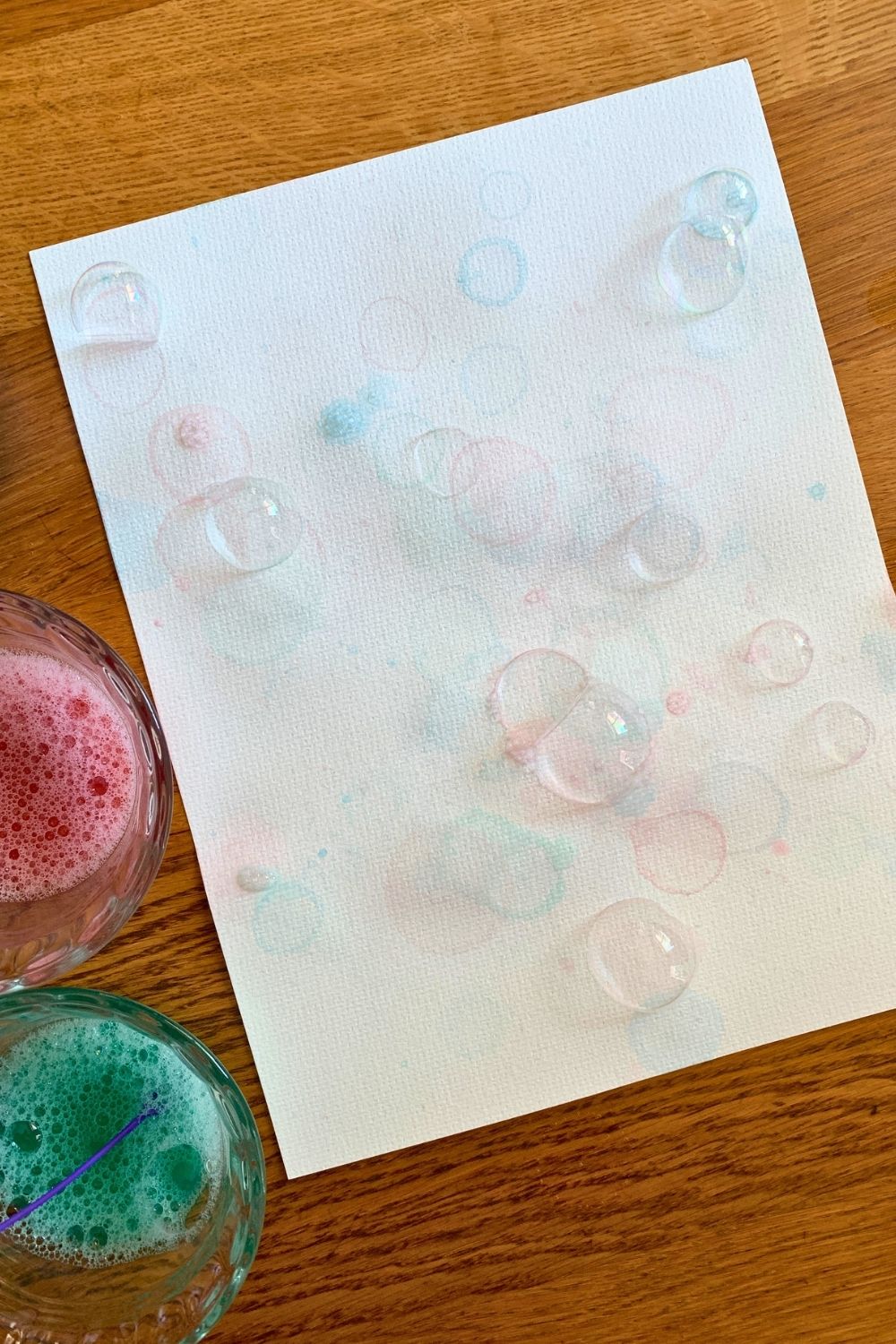 Soapy red, blue, and green bubbles resting on watercolor paper.
