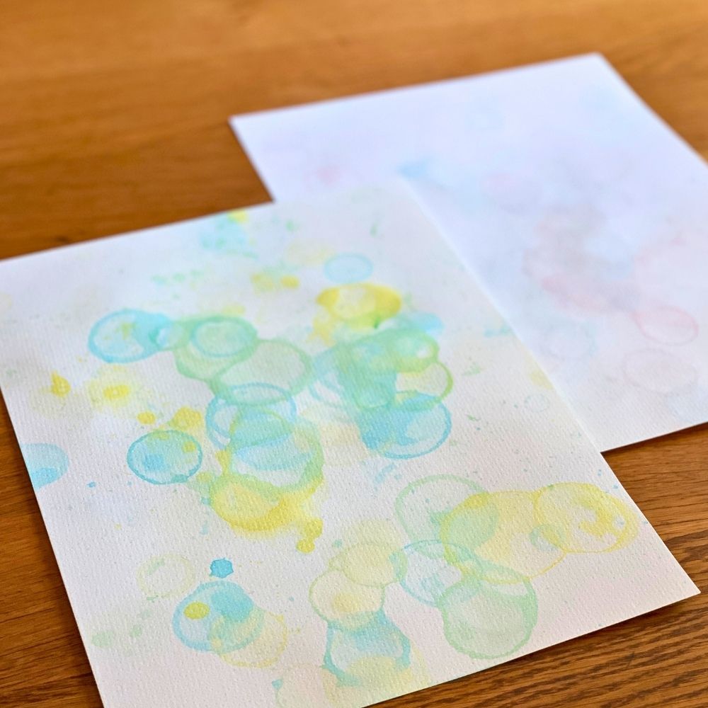 Bubble art on watercolor paper made by blowing paint soap bubbles.