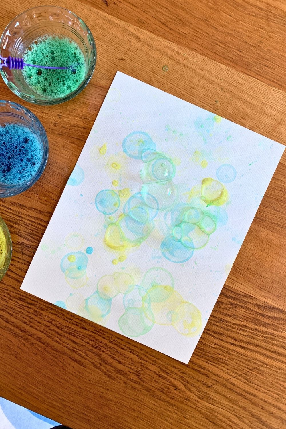 Bubble paint art made by blowing blue, yellow, and green food dye mixed with dish soap.
