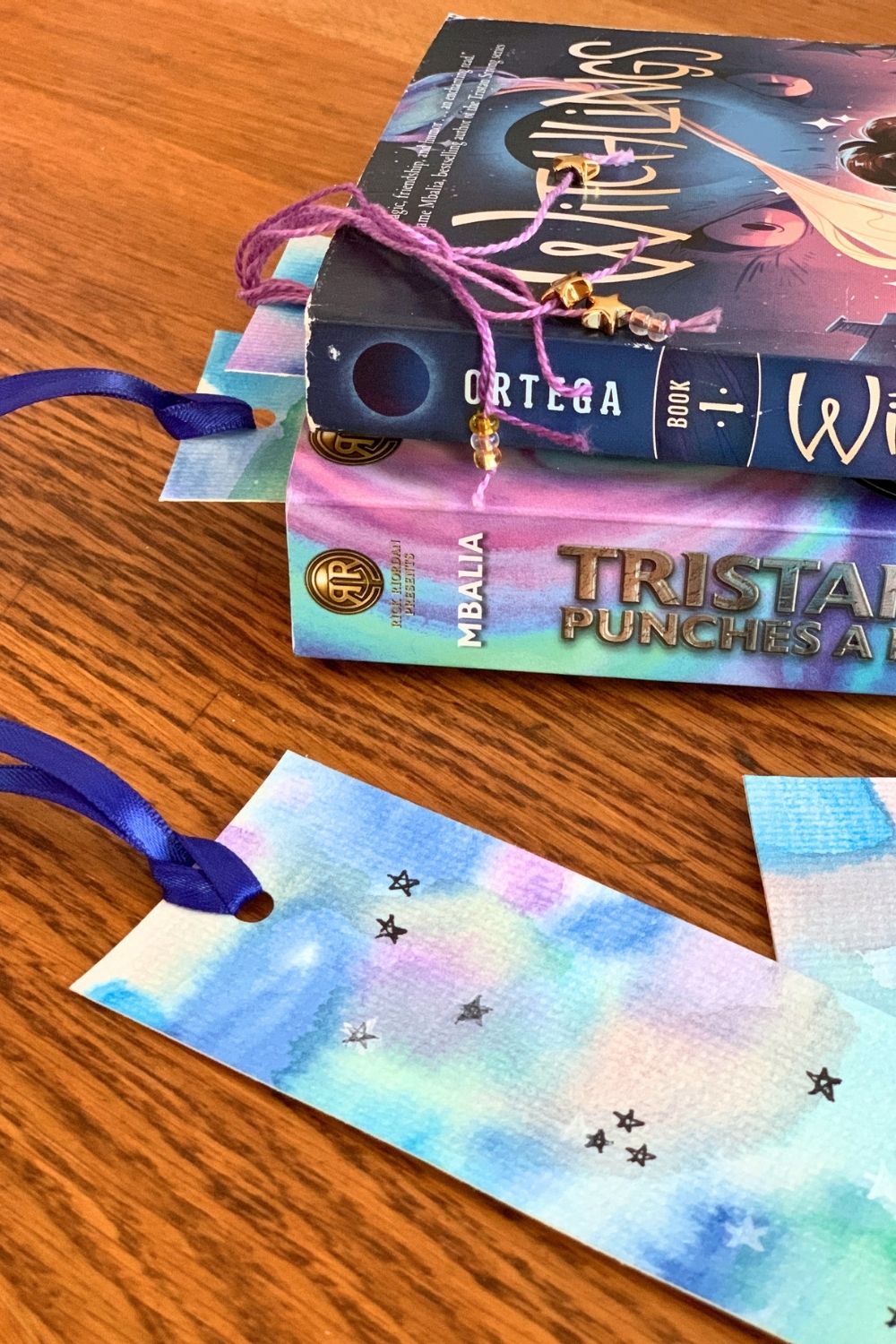 Blue and green watercolor space bookmarks with ink stars and ribbon tassels.